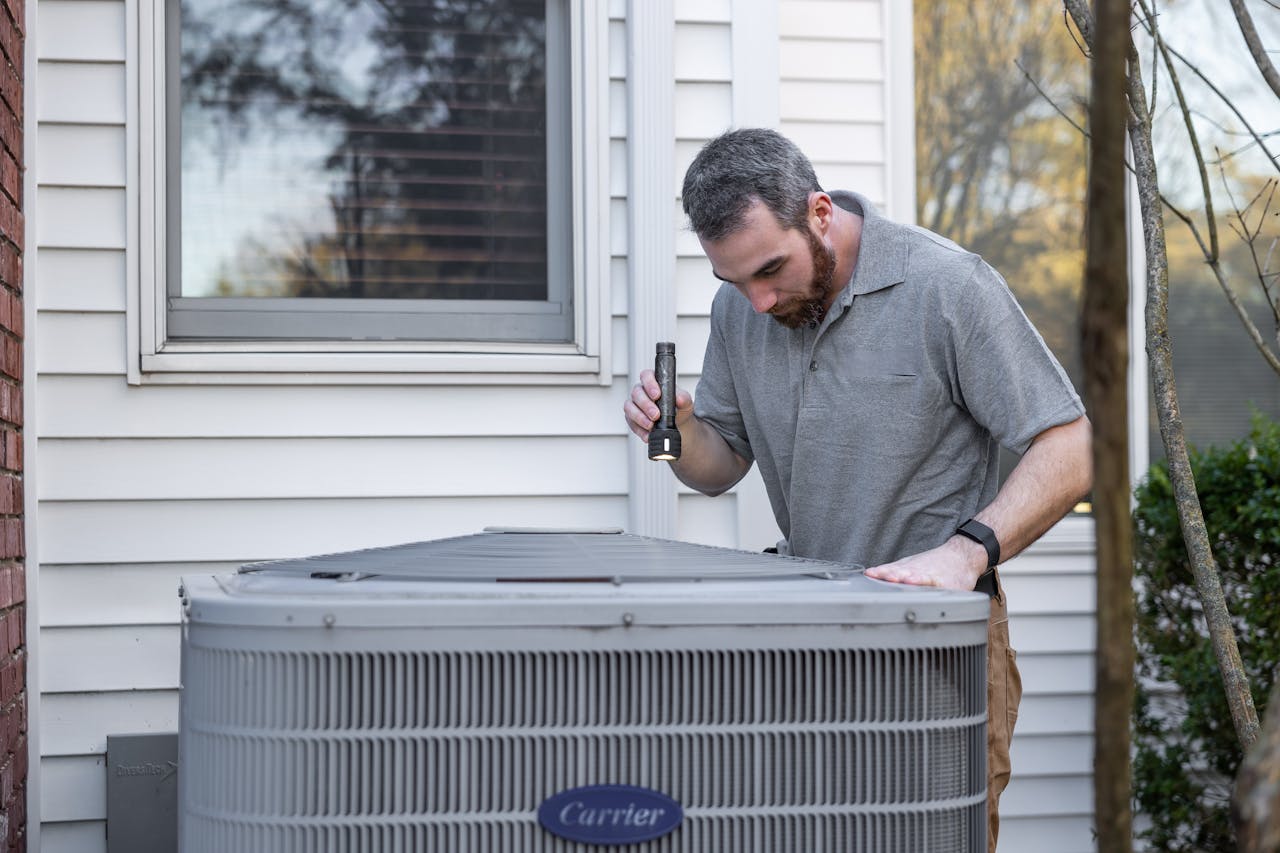 About A technician inspects an outdoor HVAC unit for maintenance.